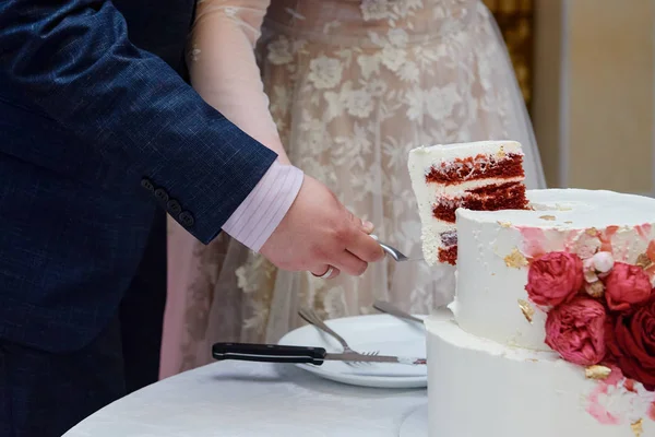 Noiva feliz e noivo corte bolo de casamento decorado com flores vermelhas rosa no restaurante, espaço de cópia. Festa de casamento — Fotografia de Stock