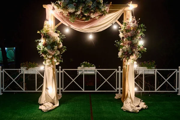 Nacht Hochzeitszeremonie mit Bogen, Blumen, Stoff und Glühbirnen auf dem Hinterhof im Freien, Kopierraum. Hochzeitsdekor — Stockfoto