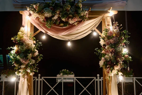 Ночная свадебная церемония с аркой, цветами, тканями и лампочками на заднем дворе, копировальное пространство. Свадебный декор — стоковое фото