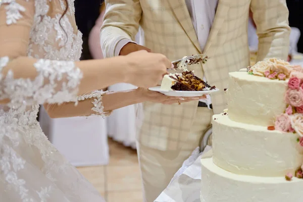 Noiva feliz e noivo corte bolo de casamento decorado com flores de rosa no restaurante, espaço de cópia. Festa de casamento — Fotografia de Stock