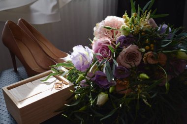 Pembe, mor güller ve yeşillik gelin buketi, bej kadın ayakkabıları, ahşap takvim ve siyah arka planda altın alyanslar, kopya alanı. Düğün konsepti