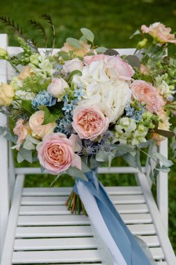 Gelin buketini, pembe gülleri, mavi çiçekleri ve dışarıdaki tahta koltukta yeşilliği kapatın. Düğün konsepti