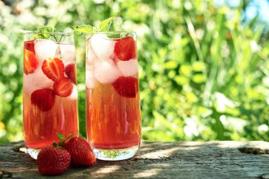 Yeşil arka plan açık, açık havada ahşap masada gözlük buz ve nane ile taze çilek limonata. Soğuk yaz içkisi. Berry kokteyl ile Köpüklü cam