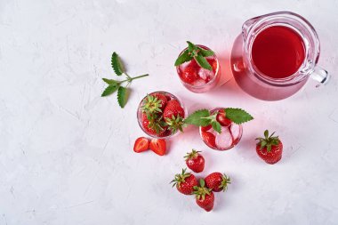 Buzlu taze çilekli limonata ve beyaz masada sürahi, kopyalama alanı. Soğuk yaz içkisi. Meyve kokteyli ile köpüklü bardaklar. Üst manzara, düz uzanma