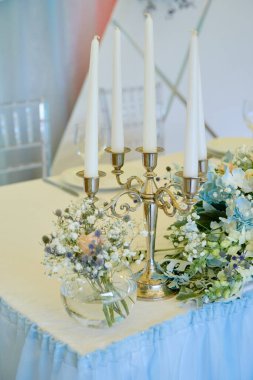 Çiçek aranjmanı ve şamdandaki mumlar restorandaki düğün masasında, fotokopi odasında. Cam vazoda bir buket kır çiçeği. Lüks düğün süslemeleri