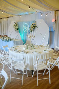 Masa seti, köpüklü şarap bardakları ve çatal bıçak takımı, kopyalama alanı. Lüks düğün resepsiyonunda. Yuvarlak masa ve beyaz ahşap sandalyeler restoranda düğün yemeği için servis ediliyor.