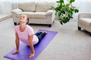 Pratik yoga adlı genç bir kadın portresi kapalı ev, uzay kopyalayın. Kobra poz, tam uzunlukta pratik kız. Rahatlatıcı ve yoga yapıyordum. Sağlık ve sağlıklı yaşam tarzı. Bhujangasana