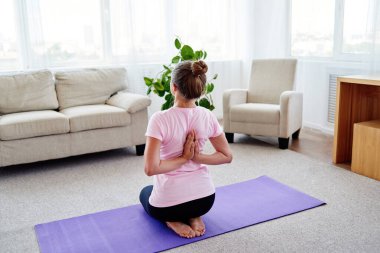 Genç kadın pratik yoga arkasından evde namaste ile kapalı. Kız ters dua poz, sırt ve omuzlar germe, kopya alanı, çalışma yapıyor. Sağlıklı yaşam tarzı