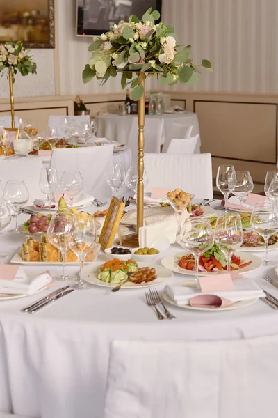 Table setting with blank guest card, white plate with pink napkin, cutlery and flowers on table, copy space. Place setting at wedding reception. Table served for wedding banquet in restaurant