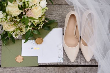Lüks düğün davetiyeleri, alyanslar, zarif gelin ayakkabıları ve ahşap arka planda gelin buketi. Balayı ve düğün kavramı. Üst manzara, düz uzanma
