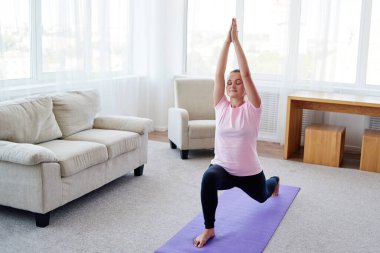 Evde denge yoga asana Virabhadrasana pratik genç yogini kadın Portresi, uzay kopyalamak. Rahatlamak ve yoga yapmak. Sağlıklı yaşam ve sağlıklı yaşam tarzı. Tam uzunlukta çekim 