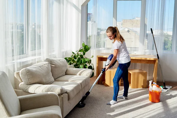 穿着白衬衫和牛仔裤的年轻女子的画像 沙发下的清洗地毯 客厅里有吸尘器 复制空间 家务劳动 清洁卫生和家务活概念 — 图库照片