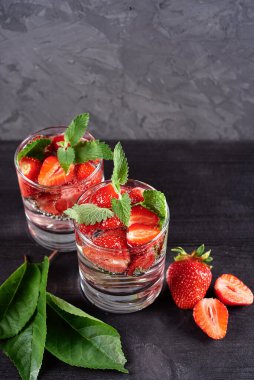 Çilekli su ve ahşap masa zemininde köpüklü bardaklarda nane şekeri, kopyalama alanı. Soğuk yaz içkisi. Maden suyu.