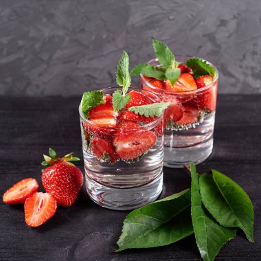 Çilekli su ve ahşap masa zemininde köpüklü bardaklarda nane şekeri, kopyalama alanı. Soğuk yaz içkisi. Maden suyu.