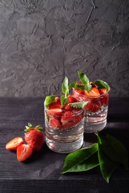 Çilekli su ve ahşap masa zemininde köpüklü bardaklarda nane şekeri, kopyalama alanı. Soğuk yaz içkisi. Maden suyu.