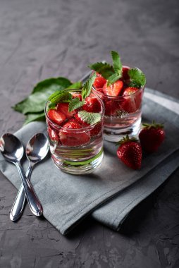 Çilekli su ve nane şekerli bardaklar beton masada gri peçete, kopyalama alanı. Soğuk yaz içkisi. Maden suyu.
