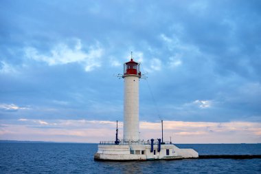 Gün batımında denizdeki kırmızı ve beyaz deniz feneri, kopyala uzayı. Deniz manzarası ve deniz feneri. Karadeniz