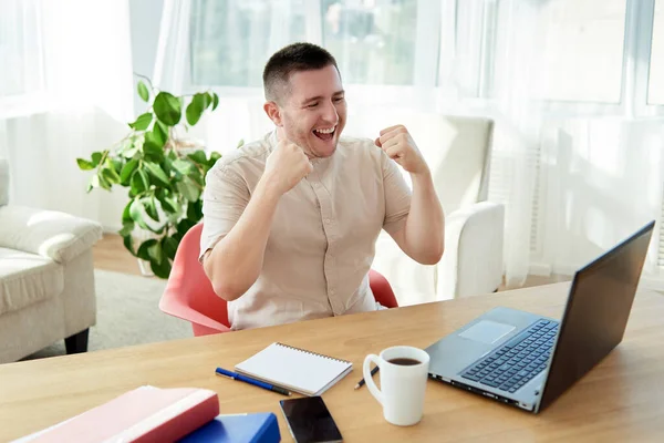 Heyecanlı genç adam yumruklarını kaldırarak zafer kazanıyor. Mutlu adam görevini tamamladı ve görevdeki başarısını kutladı. Ben bir kazananım! Ah evet! Yaptım! Yapılan işten memnun.