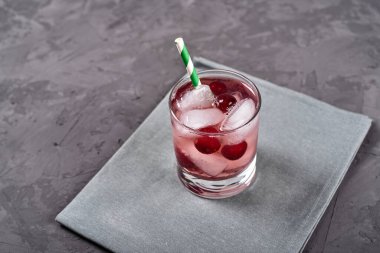 Buzlu, nane şekerli ve kağıt kamışlı taze vişneli limonata gri masa zemininde, kopyalama alanı. Soğuk yaz içkisi. Meyve kokteyli.