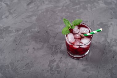 Buzlu, nane şekerli ve kağıt kamışlı taze vişneli limonata gri masa zemininde, kopyalama alanı. Soğuk yaz içkisi. Meyve kokteyli.