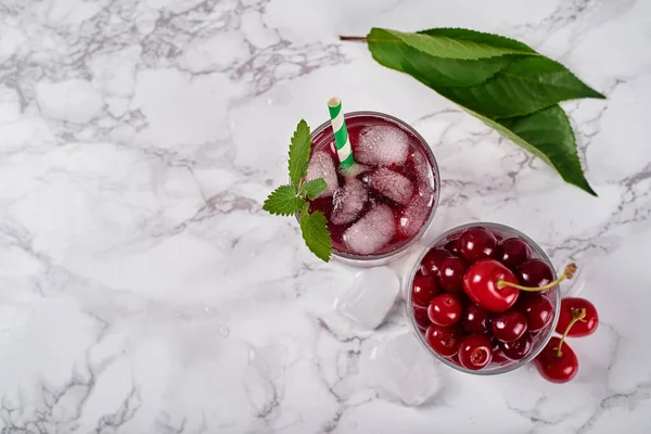 テーブルの上の輝くガラスで氷 ミントと紙のわらで新鮮なチェリーレモネード コピースペース 冷たい夏の飲み物 ベリーカクテル — ストック写真