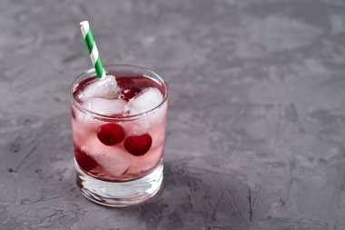 Buzlu, nane şekerli ve kağıt kamışlı taze vişneli limonata gri masa zemininde, kopyalama alanı. Soğuk yaz içkisi. Meyve kokteyli.