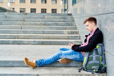 Üniversite kampüsünde merdivenlerde oturan, cep telefonu kullanan, daktilo kullanan, internette sörf yapan, dinlenen, kopyalayan umutsuz bir öğrenci. Teknoloji, eğitim kavramı