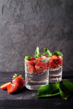 Çilekli su ve ahşap masa zemininde köpüklü bardaklarda nane şekeri, kopyalama alanı. Soğuk yaz içkisi. Maden suyu.