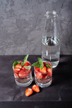 Çilekli su ve ahşap masa zemininde köpüklü bardaklarda nane şekeri, kopyalama alanı. Soğuk yaz içkisi. Maden suyu.