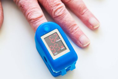 Erkek parmağında kan oksijeni ölçer. Beyaz arka planda izole edilmiş. İngiltere