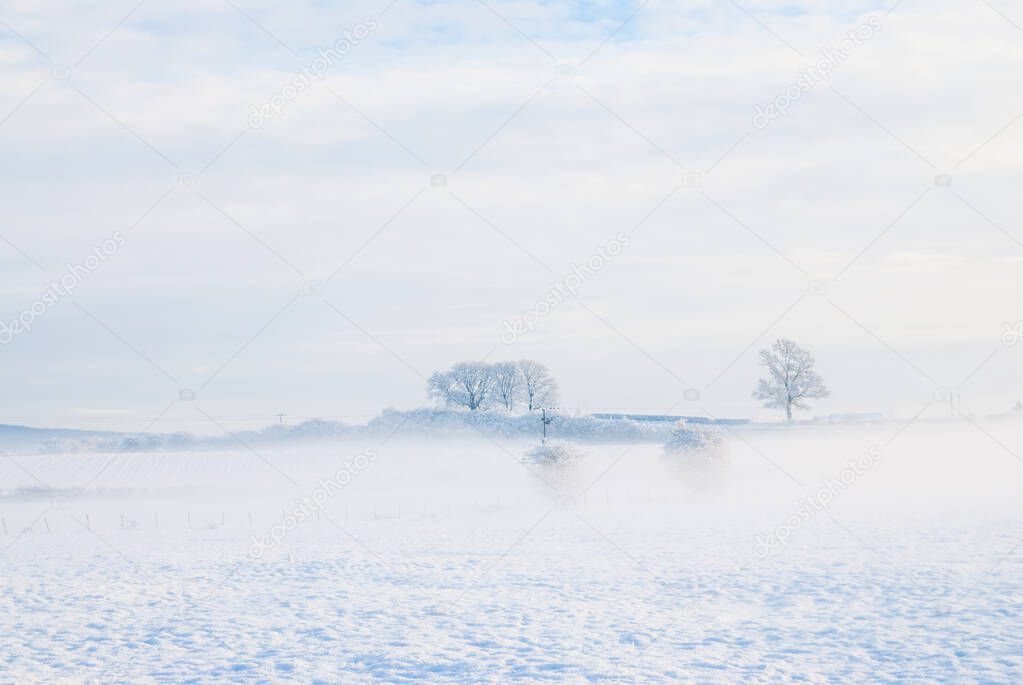 a simple background landscape with snow covered fields and distant trees half obscured by mist UK