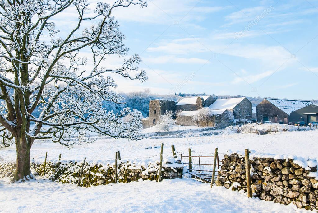 Beetham Hall on a snowey Winters day with dry stone wall and gate in foreground UK