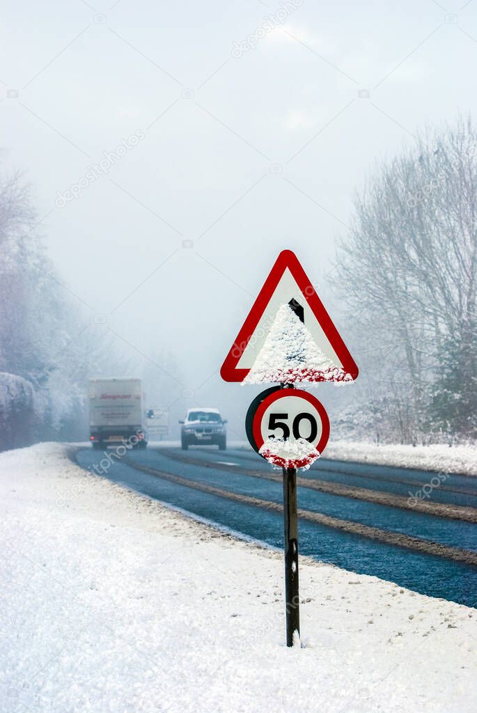 Snowy road with traffic sign and heavy snowfall on a country road.