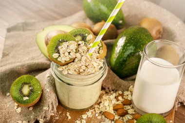 Çuval bezinin yanında kivi, avokado, yulaf ezmesi ve yağsız sütten yapılmış taze meyve püresi. Üstte madalyası var. Köyde taze malzemelerle sabah yemeği. Kapatın. Üst görünüm.