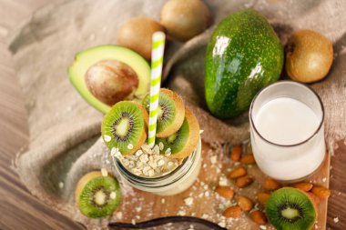 Çuval bezinin yanında kivi, avokado, yulaf ezmesi ve yağsız sütten yapılmış taze meyve püresi. Üstte madalyası var. Köyde taze malzemelerle sabah yemeği. Kapatın. Üst görünüm.