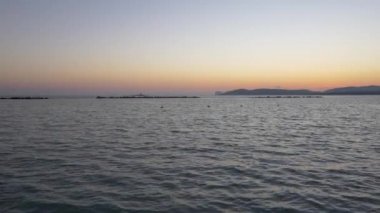 Alghero sahilde günbatımı. Sahilde yürüyüş insanlar. 