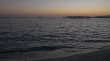 Alghero sahilde günbatımı. Sahilde yürüyüş insanlar. 