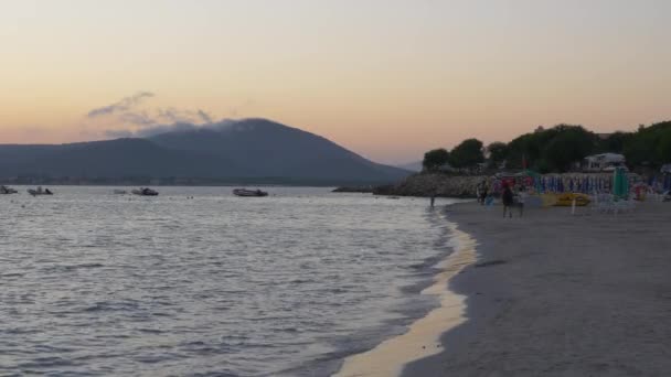 Sunset on the Alghero beach. People walking on the beach. — Stock Video