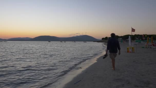 Захід сонця на пляжі Альгеро. Люди, що йдуть на пляжі. — стокове відео