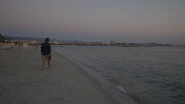 Sunset on the Alghero beach. People walking on the beach. — Stock Video