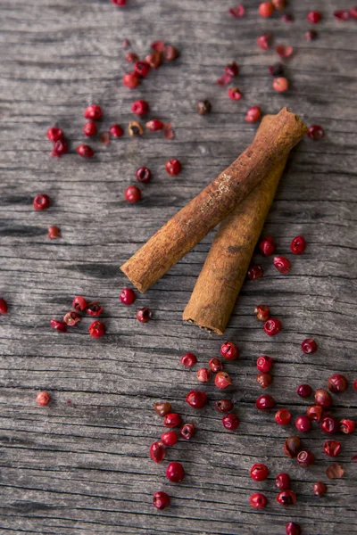 Cinnamon sticks and rose pepper at a wooden background