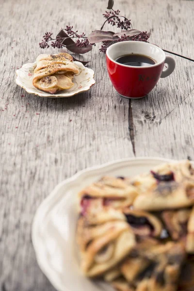 Postre casero. Rollo de postre con plátanos y, manzanas y semillas de amapola en un plato blanco y taza de café rojo — Foto de Stock