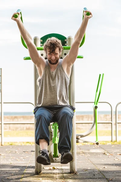 Active man exercising on chest press outdoor.