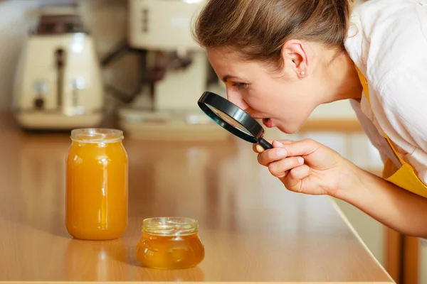 Vrouw inspectie van honing met Vergrootglas. — Stockfoto