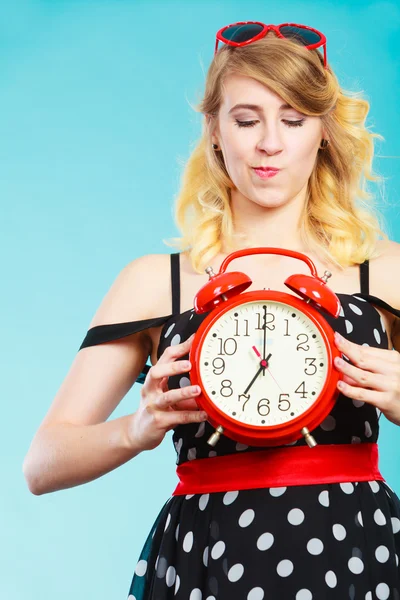 Blond meisje met wekker op blauw. — Stockfoto