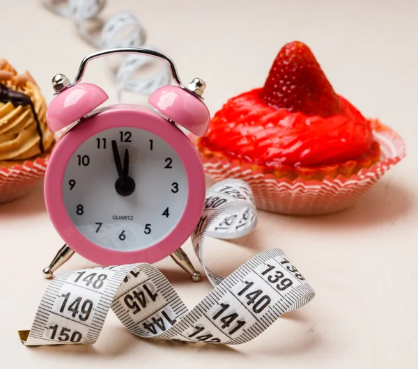 Cinta métrica de alimentos dulces y reloj en la mesa —  Fotos de Stock