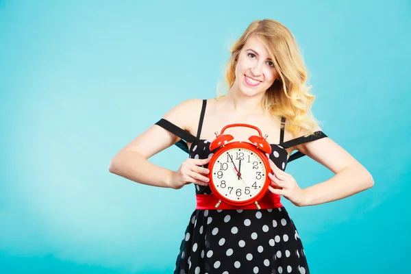 Smiling girl with alarm clock on blue. — Stock Photo, Image