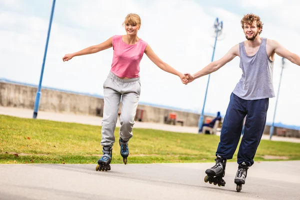 Pareja joven patinando en parque tomados de la mano . — Foto de Stock