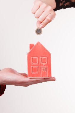 İnsanlar elleriyle küçük ev ve gümüş sikke.