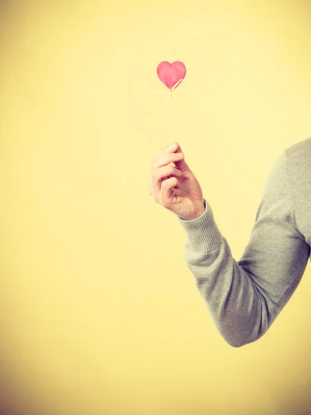 Person holding heart on stick.